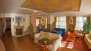 A spacious living room with a fireplace, sofas, and a round coffee table. - Mediterran Hotel (Budapest)
