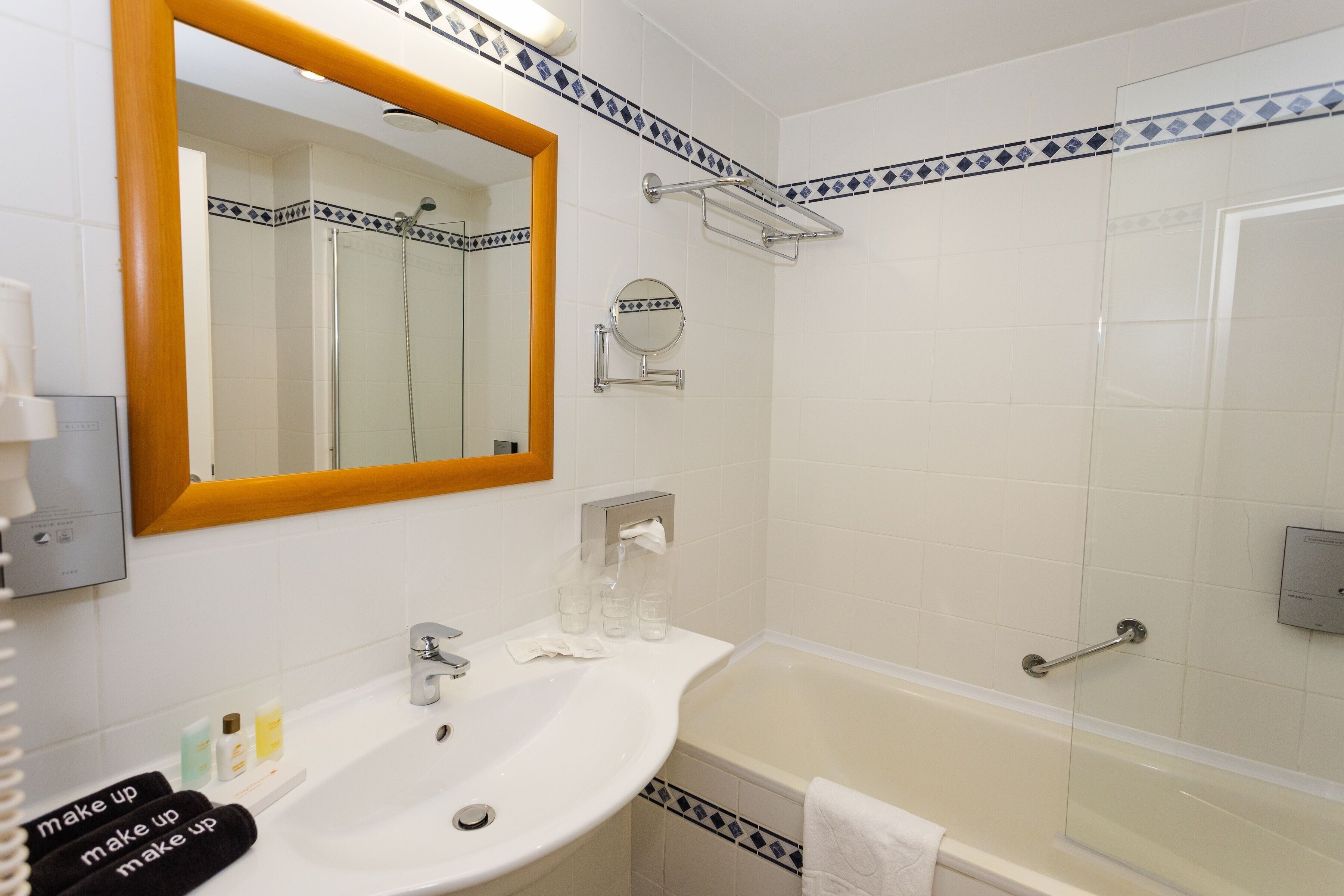 A bathroom with a sink, mirror, shower, and towel rack.