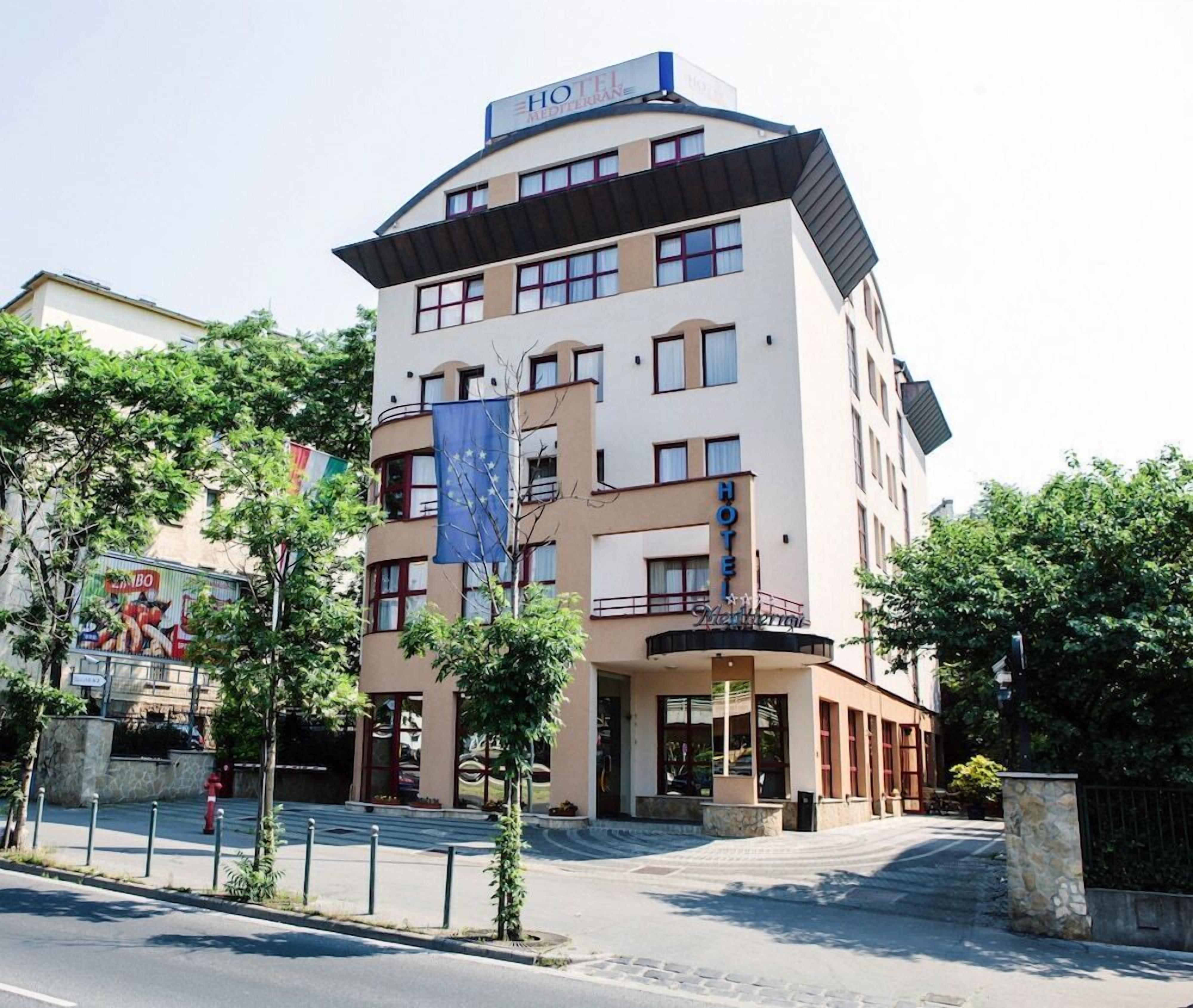 Et moderne hotel med flere etager, med både altaner og en markant indgang.