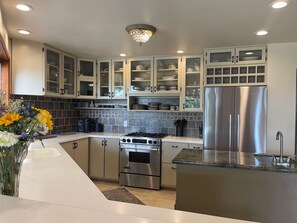A modern kitchen with stainless steel appliances, white cabinetry, and a decorative light fixture.