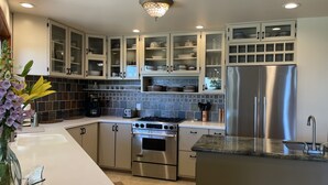 A modern kitchen with white cabinetry, a stainless steel refrigerator, a built-in oven, and a gas stove. - Spacious South Hill View Home, Private Mountain Setting & Hot Tub (Spokane)