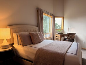 A neatly made bed with a headboard, a bedside lamp, and a window with curtains. - Browne’s Mtn Retreat, South Hill Views and Hot Tub (Spokane)