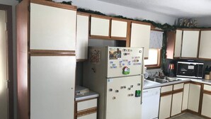 A kitchen with wooden cabinets, a refrigerator, a microwave, and a sink.