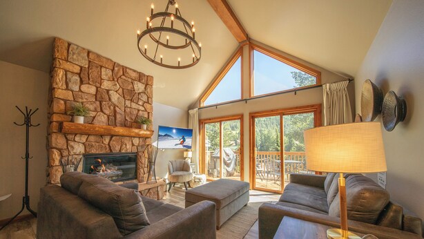 A cozy living room with a stone fireplace, comfortable seating, and large windows offering a view of the outdoors. - Snake River 1 (Keystone)