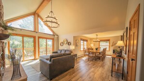 A spacious living area with a large sofa, dining table, and chairs. There are large windows providing natural light and a view of the outdoors. - Snake River 1 (Keystone)