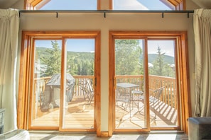 A room with large sliding glass doors leading to an outdoor deck with a table and chairs. - Snake River 1 (Keystone)