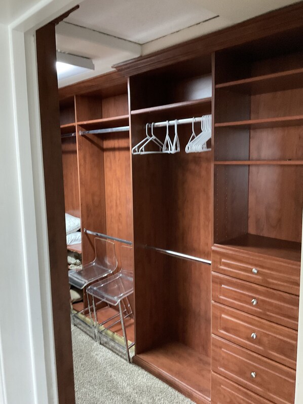 A walk-in closet with open shelves, hanging space, and drawers.