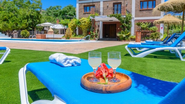 A poolside lounge with a blue towel, two glasses of white beverage, and a wooden tray with a red flower. - Casita De Rufo Cenes de la Vega by Ruralidays (Granada)