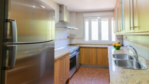 A kitchen with stainless steel appliances, wooden cabinets, a granite countertop, and a window with blinds. - Casita De Rufo Cenes de la Vega by Ruralidays (Granada)