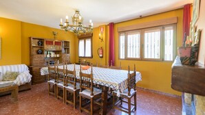 A dining area with a large table, wooden chairs, a chandelier, and a window with curtains. - Casita De Rufo Cenes de la Vega by Ruralidays (Granada)
