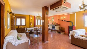 A cozy living room with a fireplace, wooden furniture, and a dining area with chairs and a table. - Casita De Rufo Cenes de la Vega by Ruralidays (Granada)