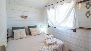A bedroom with a bed, pillows, a bedside table, a lamp, and a window with sheer curtains. - Rural las Bodegas Setenil de las Bodegas by Ruralidays (Cádiz)