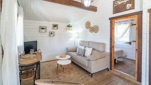 A cozy room with a sofa, a small table, a TV, and a bed with a canopy. - Rural las Bodegas Setenil de las Bodegas by Ruralidays (Cádiz)