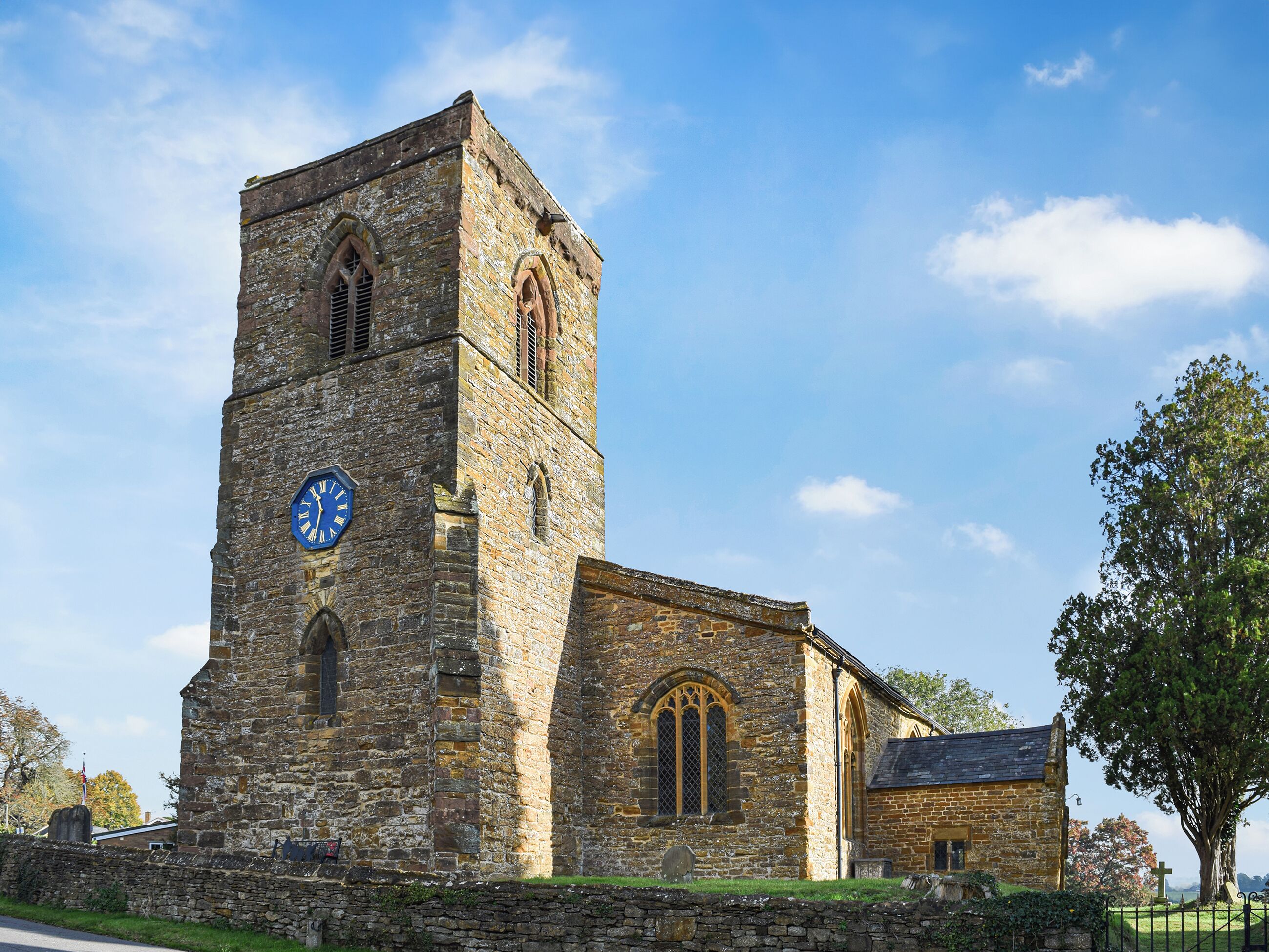 Eine historische Steinkirche mit einem Glockenturm, Rundbogenfenstern und einem kleinen Anbau.