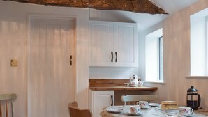 A dining area with a table set for tea, a cake, and a coffee pot. - 3 bedroom accommodation in Welton (Welton)