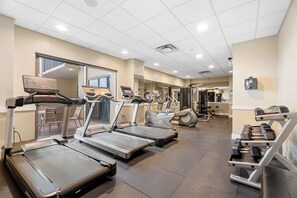 A gym with treadmills, weight machines, and dumbbells.