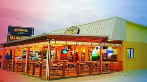 Een restaurant met terras en een neonreclame.