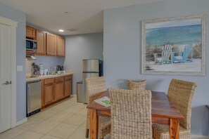 Una cocina con armarios de madera, un refrigerador y un comedor con sillas de mimbre y una mesa de madera.
