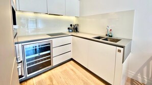 A modern kitchen with white cabinets, a built-in oven, and a stainless steel sink.