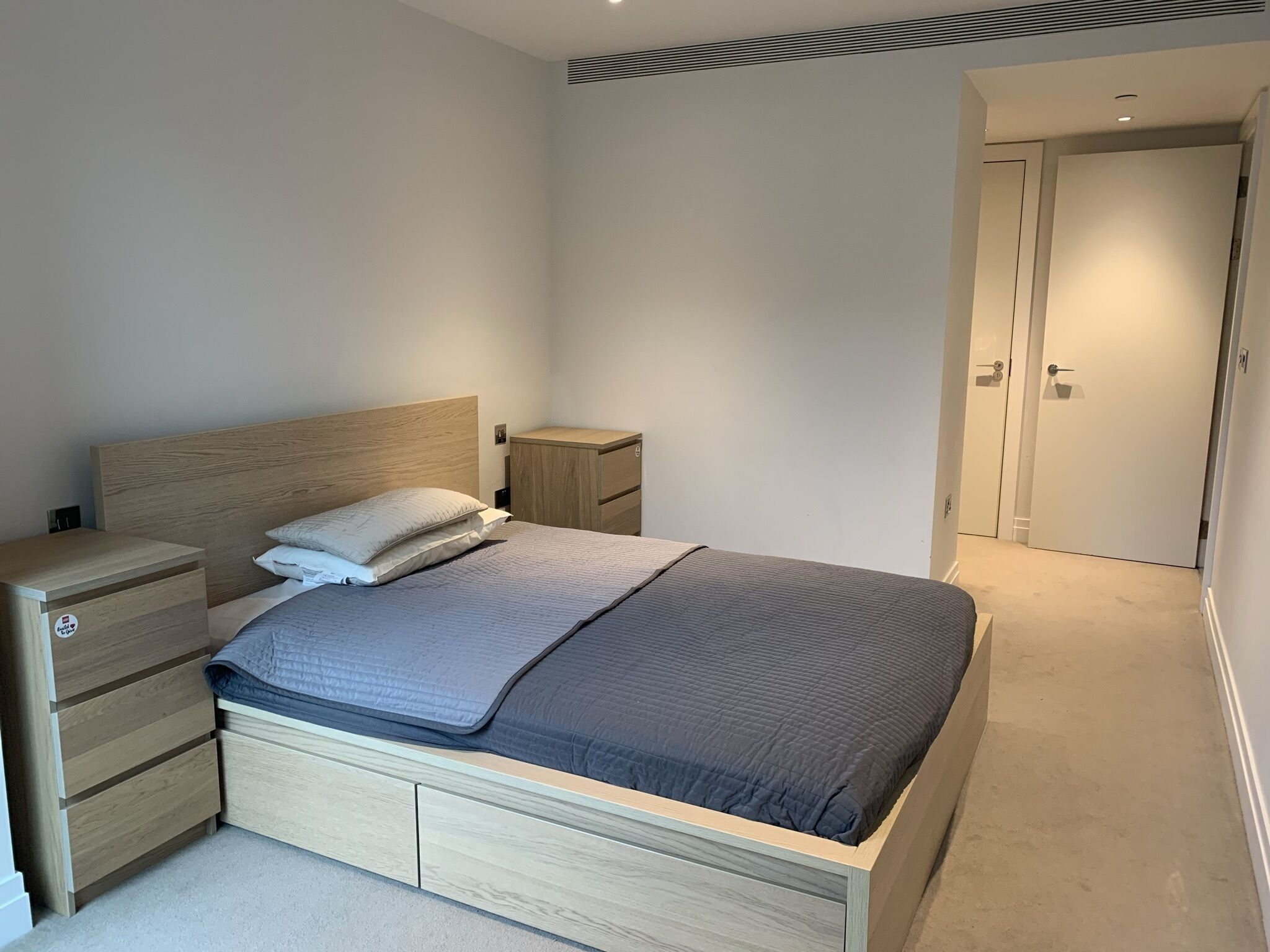 A bedroom with a bed, nightstands, a dresser, and a door.