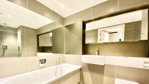 A modern bathroom with a large bathtub, a toilet, and a vanity with a mirror.