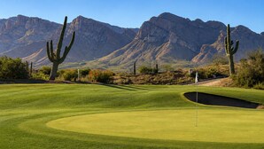 A golf course with cacti and mountains in the background.
