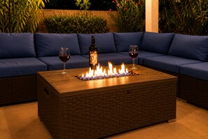 A rectangular fire feature with two wine glasses on a blue sofa. - Firepit Nights · Private Heated Pool & BBQ (Oro Valley)