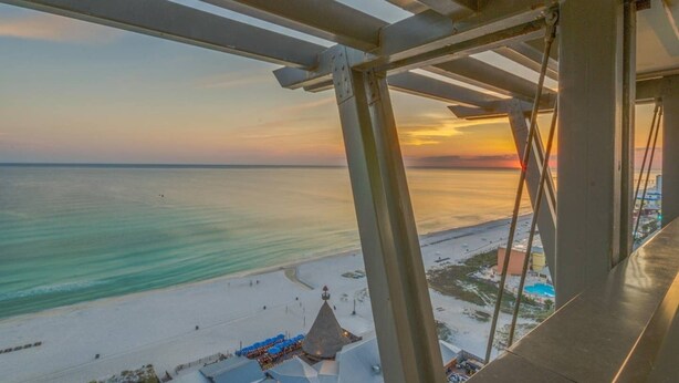 Blick auf den Strand vom Balkon aus, mit klarem Himmel und Sonnenuntergang.