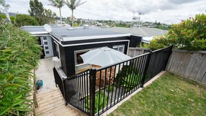 Ein wohnbereichsähnlicher Garten mit einer Holzterrasse, einem schwarzen Metallzaun und einer Terrasse mit Tisch und Stühlen.