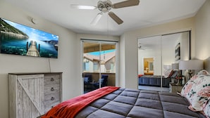 Quarto com cama, cómoda de madeira, ventoinha no teto, janela ampla e pintura de um cais.