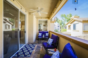 Enjoy the serene views of the neighborhood from this balcony, complete with a ceiling fan and comfortable seating.
