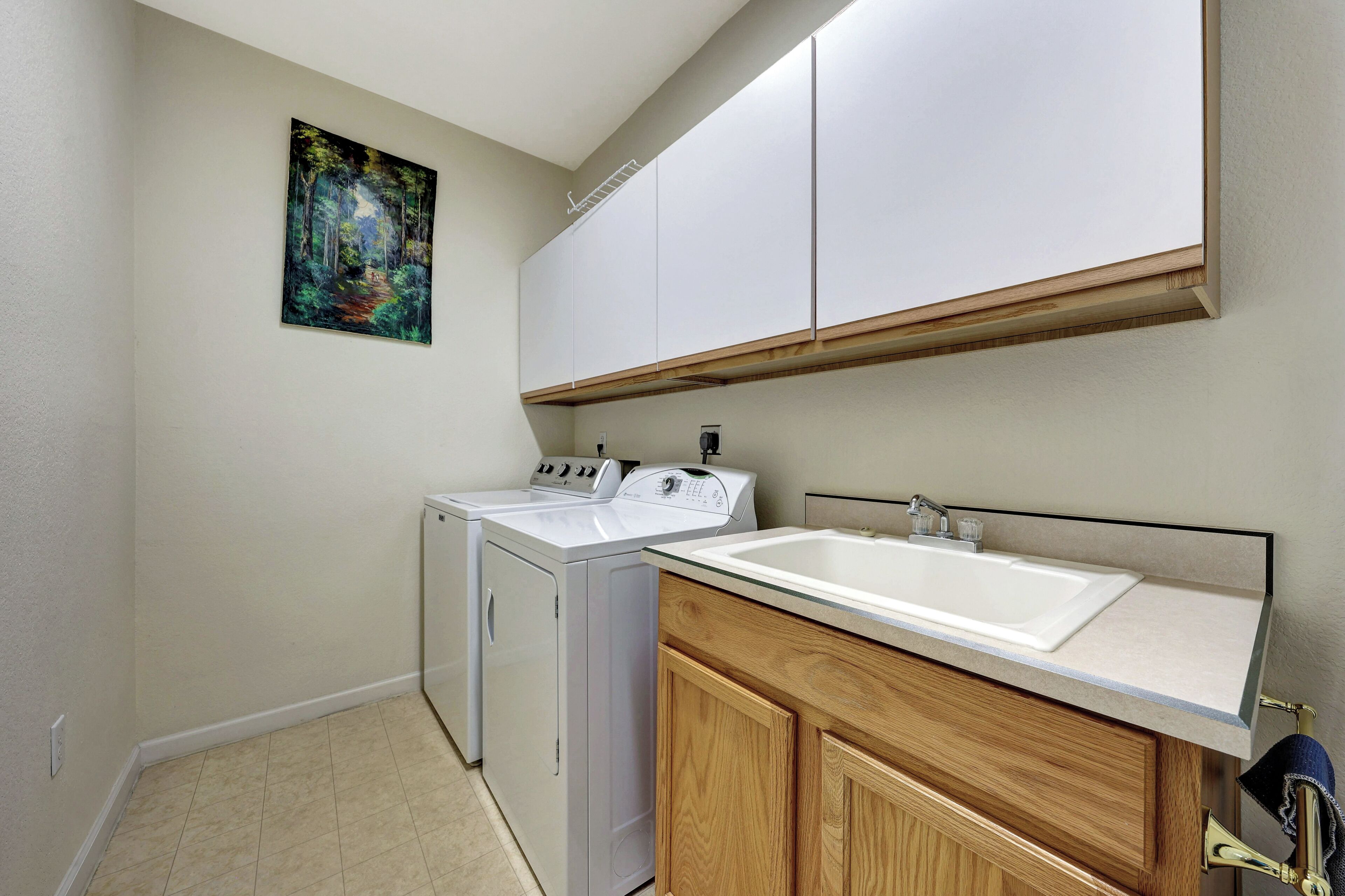 A laundry area with a washing machine, dryer, and a sink with a mirror above.