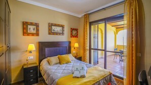 A hotel room with a bed, two bedside lamps, a large window with curtains, and a view of an outdoor area. - Residencial Las Torrecillas, Casa 15 Puente Genil by Ruralidays (Córdoba)