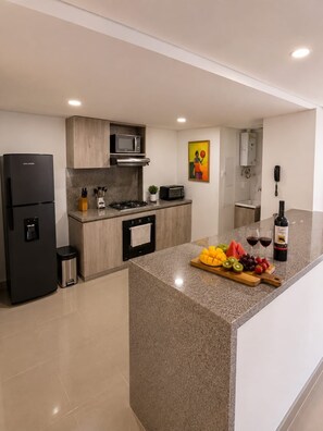 A modern kitchen with a central island, a refrigerator, microwave, and a stove.