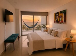 A hotel room with a bed, a bench, a TV, a large window with a view of palm trees and the ocean, and a painting on the wall. - Ocean View - Infinity Pool - WiFi - Jacuzzi (Cartagena)