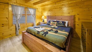 Une chambre dans une cabane en bois, avec un lit, une table de chevet et un banc en bois.