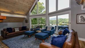Un salon spacieux avec un plafond haut, de grandes fenêtres et une vue sur un lac.