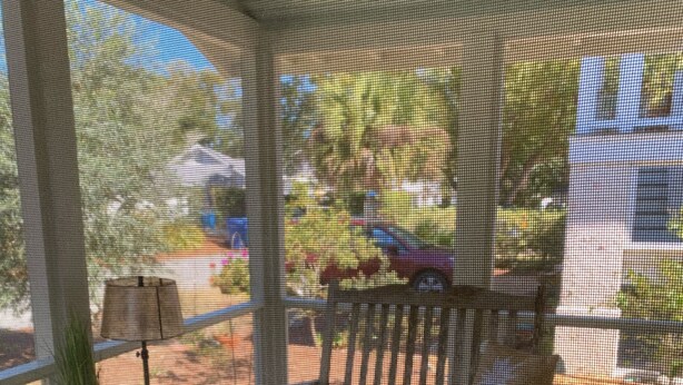 A screened porch with a patterned rug, a small table, and a bench. - Walk  to beach & 7 restaurants.  Our 1950’s 3 bed & 2 bath cottage is fantastic! (St. Simons)