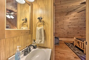 L’intérieur d’un chalet en bois comprend une salle de bain équipée d’un lavabo, d’un miroir et décorée de pommes de pin.
