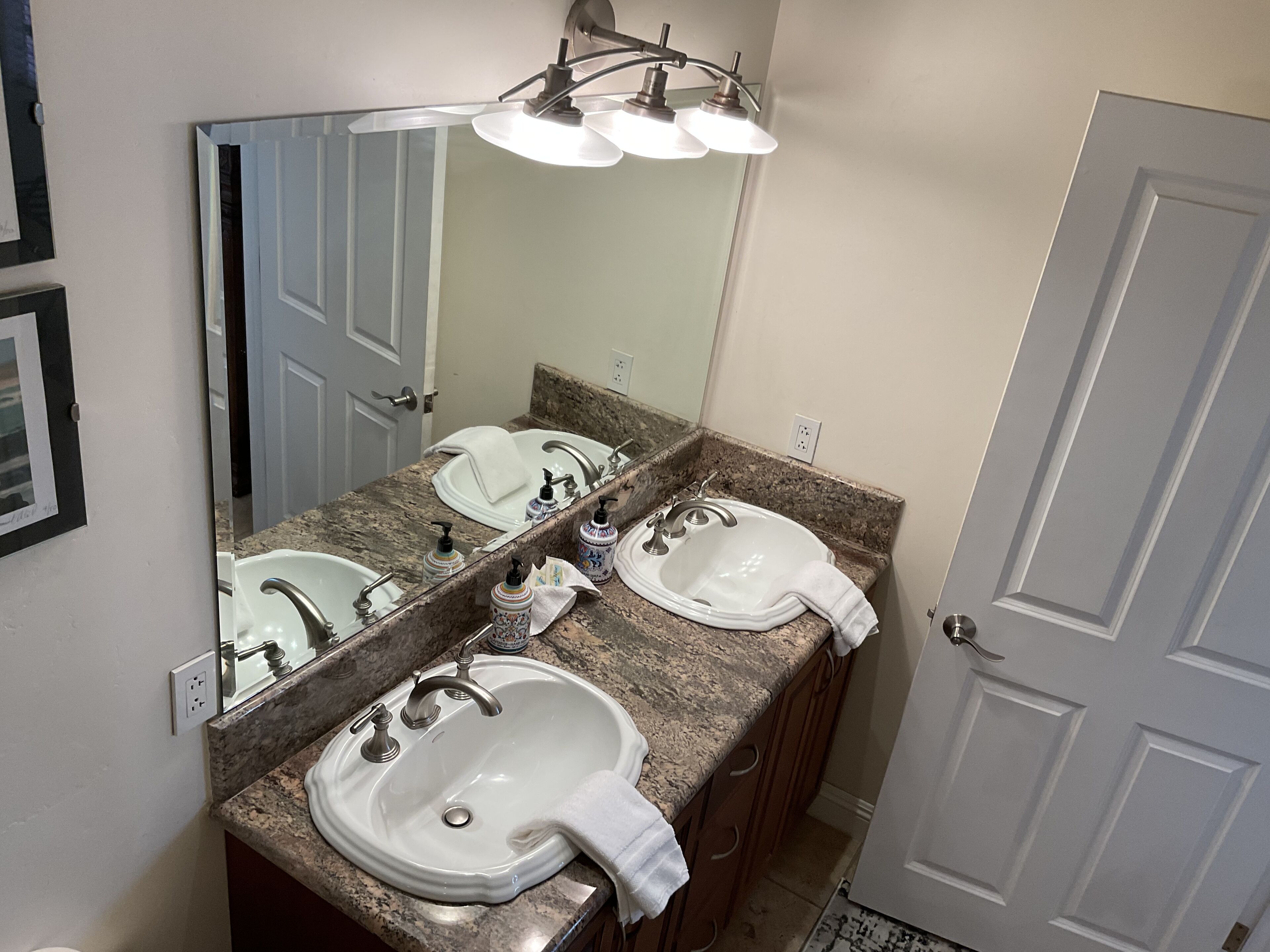 A bathroom with two sinks, a large mirror, and a door.