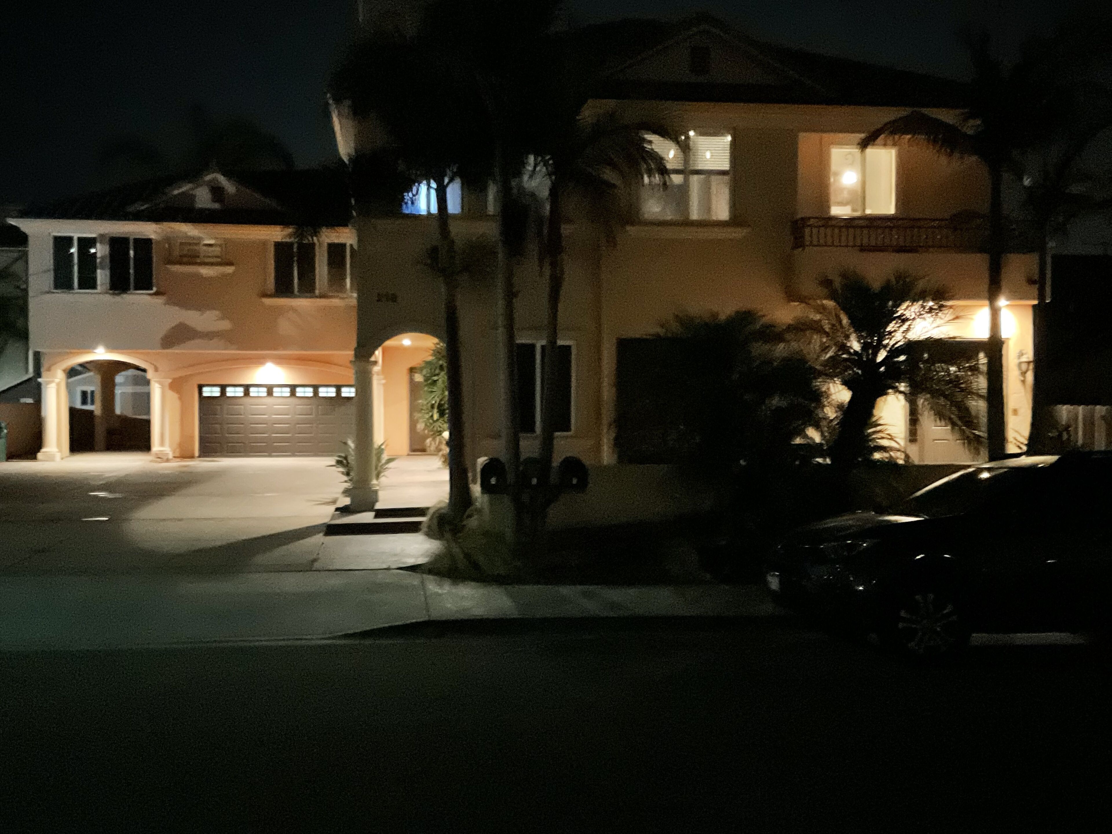 A two-story house with a garage, a driveway, and a parked car.