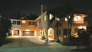 Een twee verdiepingen tellend huis met een garage, gebogen paden en een goed verlichte entree.