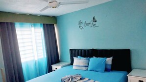 A bedroom with a bed, a nightstand, a ceiling fan, and a wall with a motivational quote.