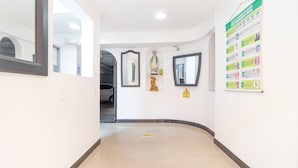A hallway with a tiled floor, a mirror, a statue, and a safety sign. - Ayenda 1086 Torre 52 (Bogotá)