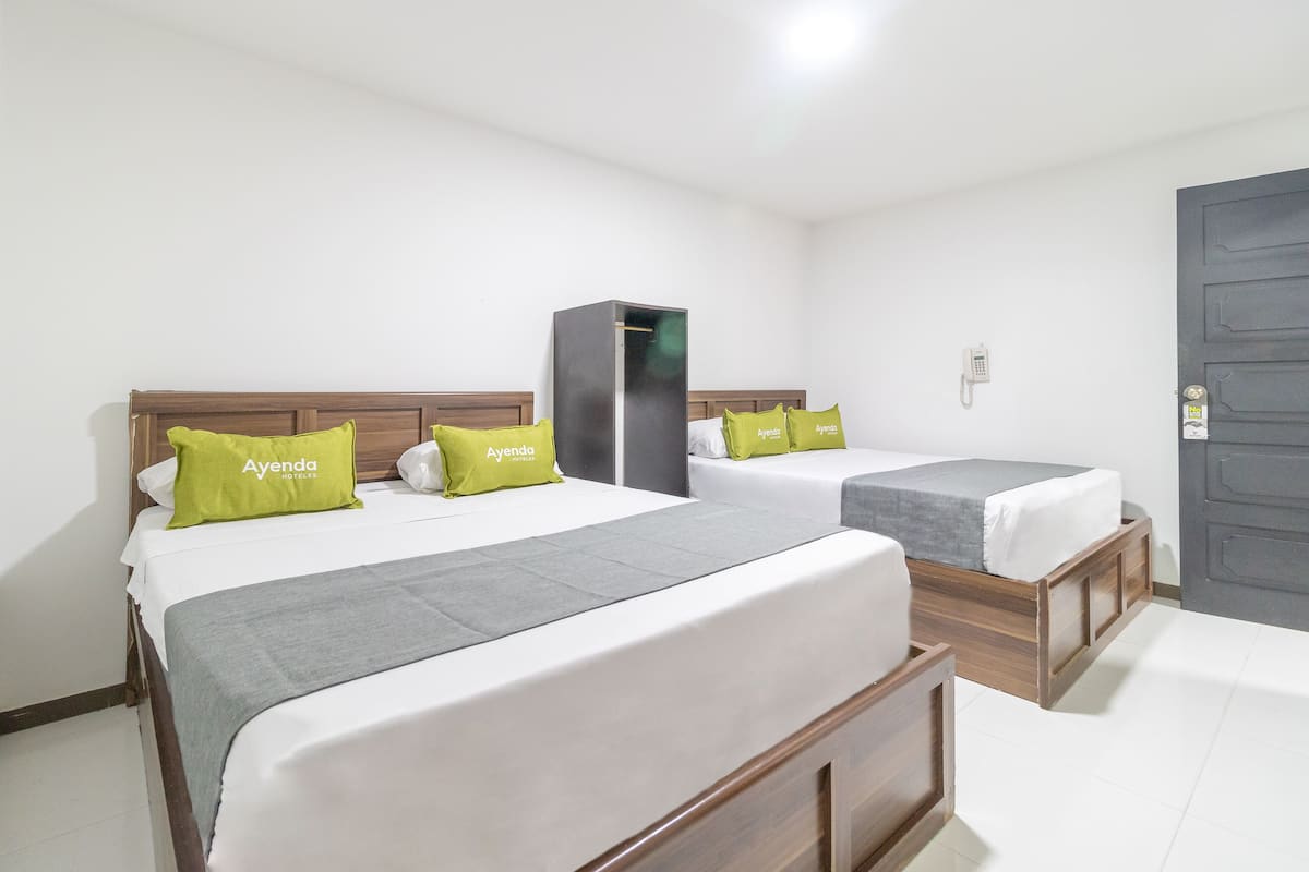 A hotel room with two beds, each with a wooden headboard and grey bedding. There is a wardrobe and a telephone on the wall.