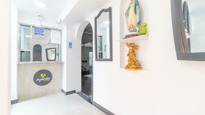 A hotel reception area with a counter, a sign indicating a public restroom, and a statue on the wall. - Ayenda 1086 Torre 52 (Bogotá)