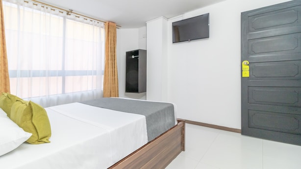 A modern hotel room with a bed, a TV mounted on the wall, and a wardrobe. - Ayenda 1086 Torre 52 (Bogotá)
