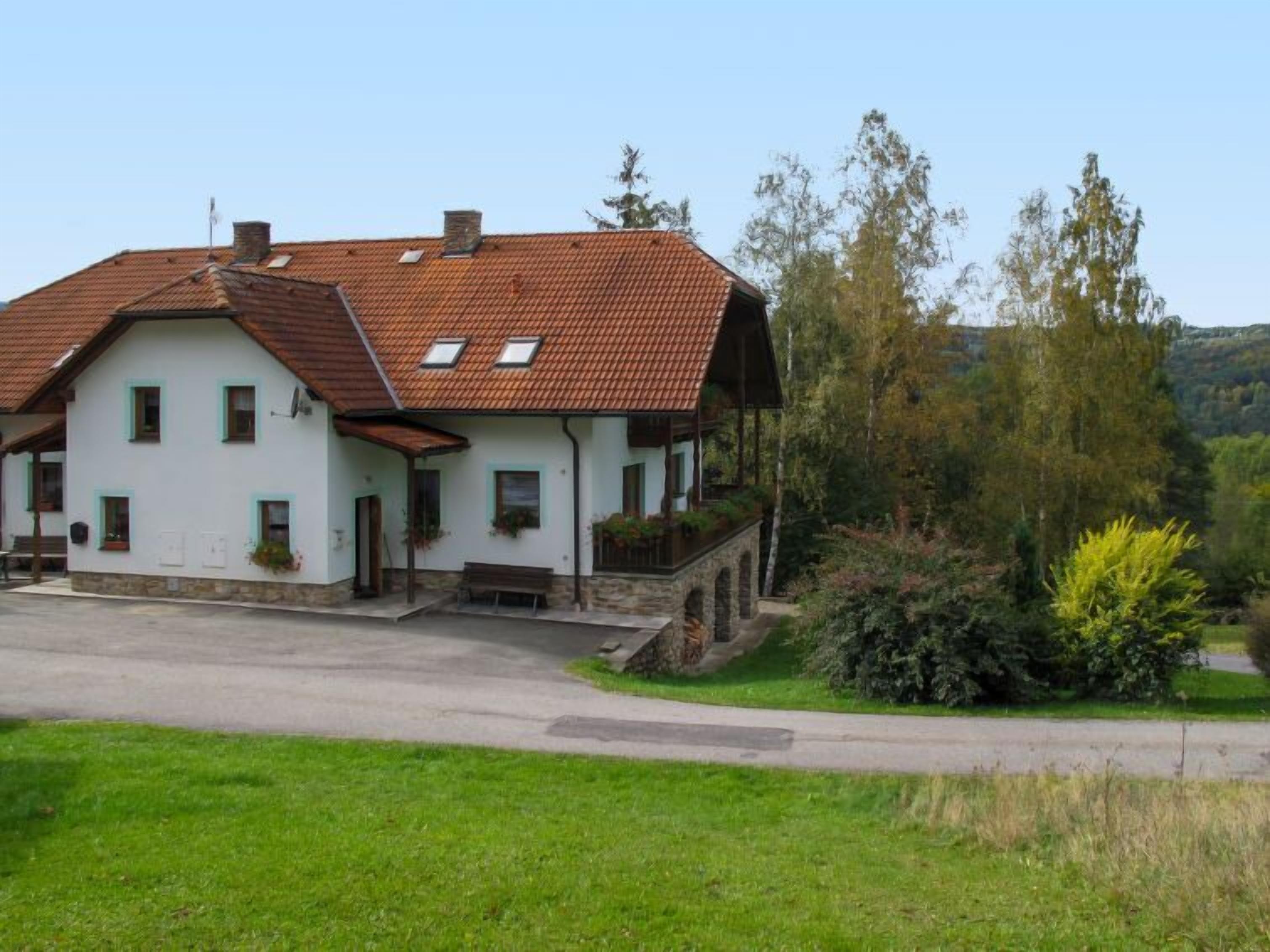 A two-story house with a sloped roof, a porch, and a stone foundation.