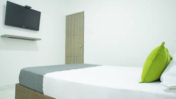 A bedroom with a bed, a television mounted on the wall, and a wardrobe.