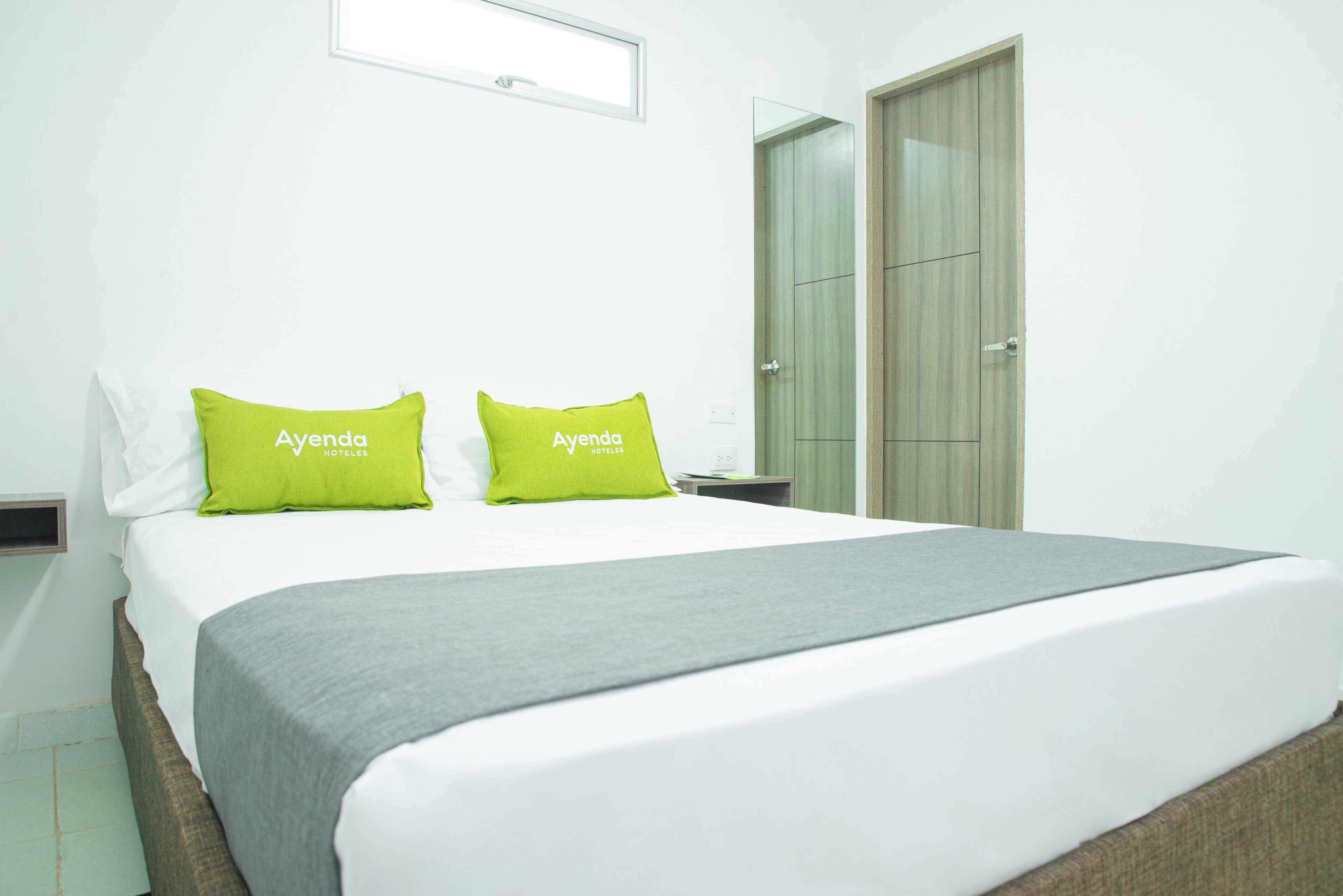 Ein Hotelzimmer mit Bett, zwei Kissen, einem Nachttisch und einem Kleiderschrank.